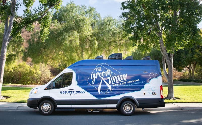 The Groom Vroom mobile grooming van parked on a tree-lined suburban street